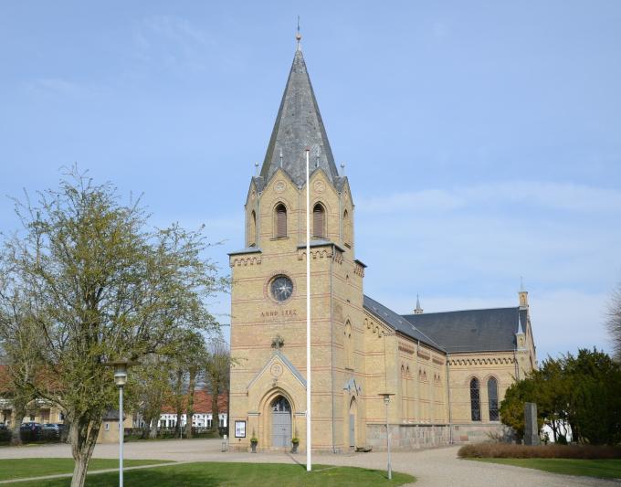 Tyrstrup Kirke er bygget i gule sten og med bælter af røde sten. Foto fra 2023.