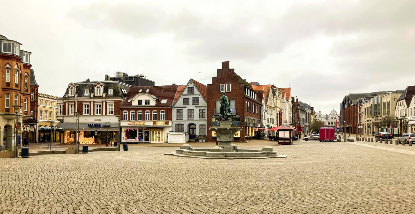 Den store markedsplads i Husum. Midt på pladsen står springvandet "Tine" fra 1905, der viser en ung fiskerkone i træsko. Foto fra 2022. Den store markedsplads i Husum. Midt på pladsen står springvandet "Tine" fra 1905, der viser en ung fiskerkone i træsko. Foto fra 2022.