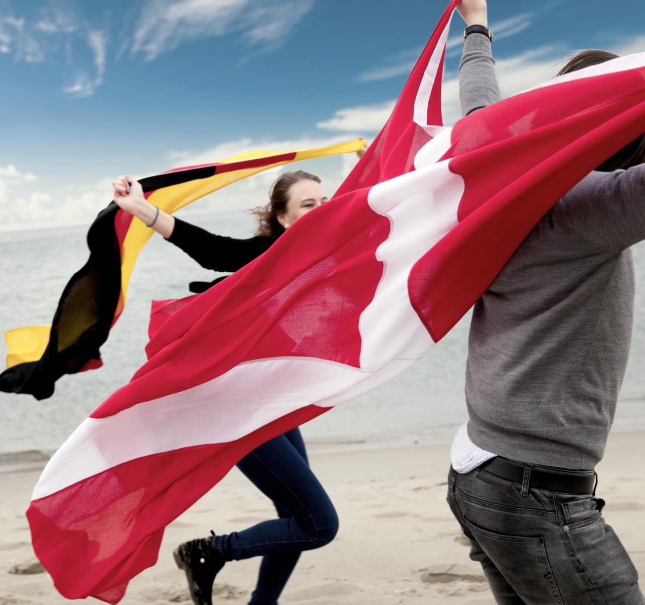 Unge på strand med dansk og tysk flag Unge på strand med dansk og tysk flag