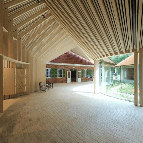 Et stort åbent og lyst ankomstområde binder de to eneste tilbageværende barakker sammen i en samlet museumsbygning.