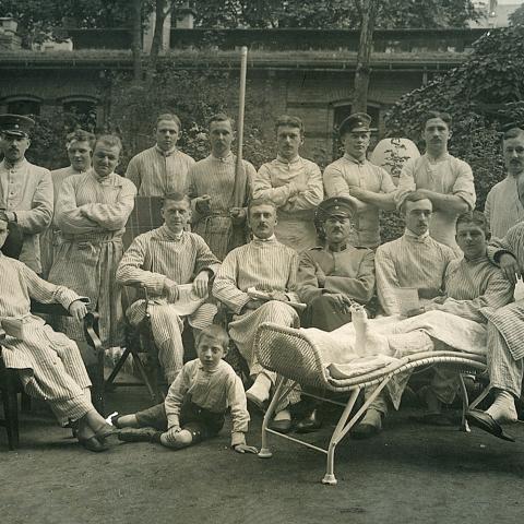 Gruppebillede af sårede soldater fra et lazaret under Første Verdenskrig 1914-1918. Fotografen hedder Joh. H. Schwiebert. Historien melder ikke noget om de to børn, der er med på billedet.