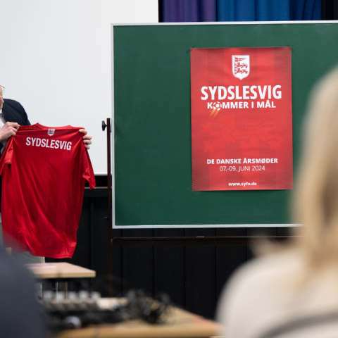 Tim Frogier de Ponlevoy, formand for Årsmødeudvalget, præsenterede den nye årsmødeplakat samt spillertrøjen for det sydslesvigske landshold til et møde i Sydslesvigsk Forening (SSF). 