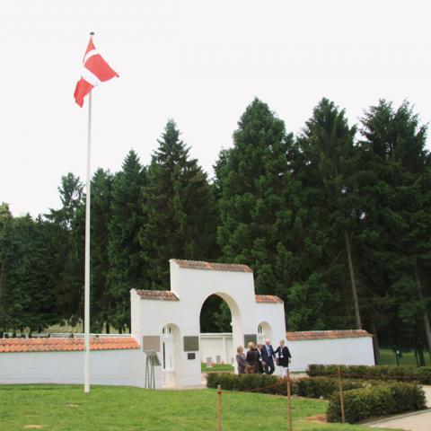 I traditionel dansk stil er den hvide mur omkring den sønderjyske kirkegård i Braine beklædt med røde teglsten.