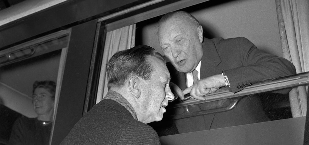 Statsminister H.C. Hansen (tv) får en snak med Vesttysklands forbundskansler Konrad Adenauer på Københavns Hovedbanegård i 1957, altså to år efter at de to regeringschefer underskrev København-Bonn Erklæringerne. Forbundskansleren er på vej til sin søns bryllup i Kalmar i Sverige og gør et kort ophold, hvor han når at veksle et par ord med den danske statsminister – ud af vinduet på sin private salonvogn.